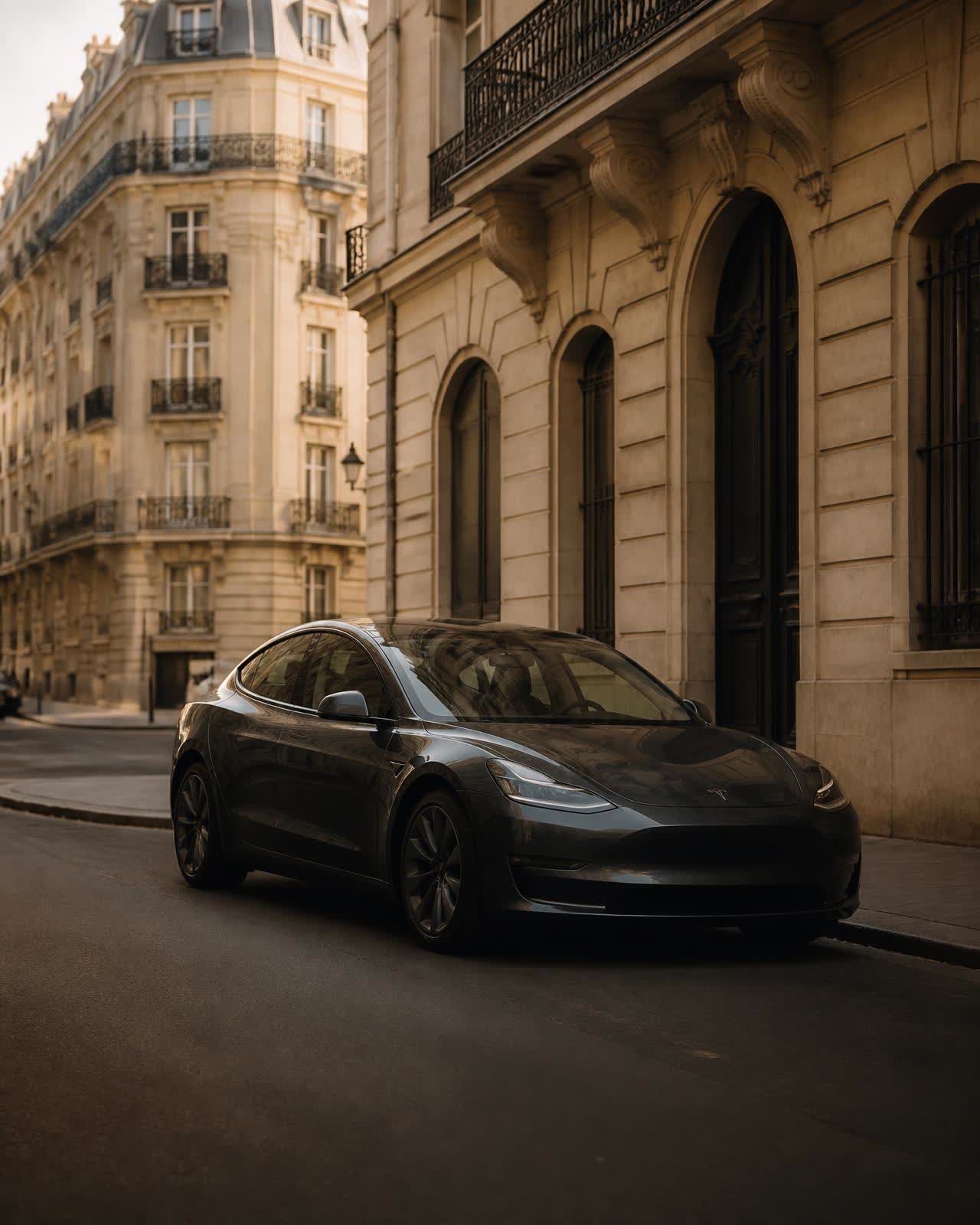 Tesla Model 3 gris foncé stationnée devant un immeuble haussmannien parisien